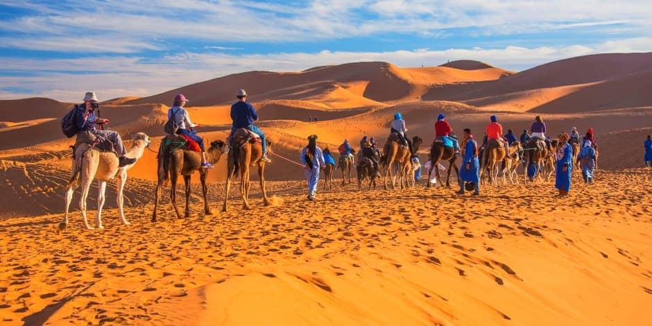 tourists riding camels in morocco desert