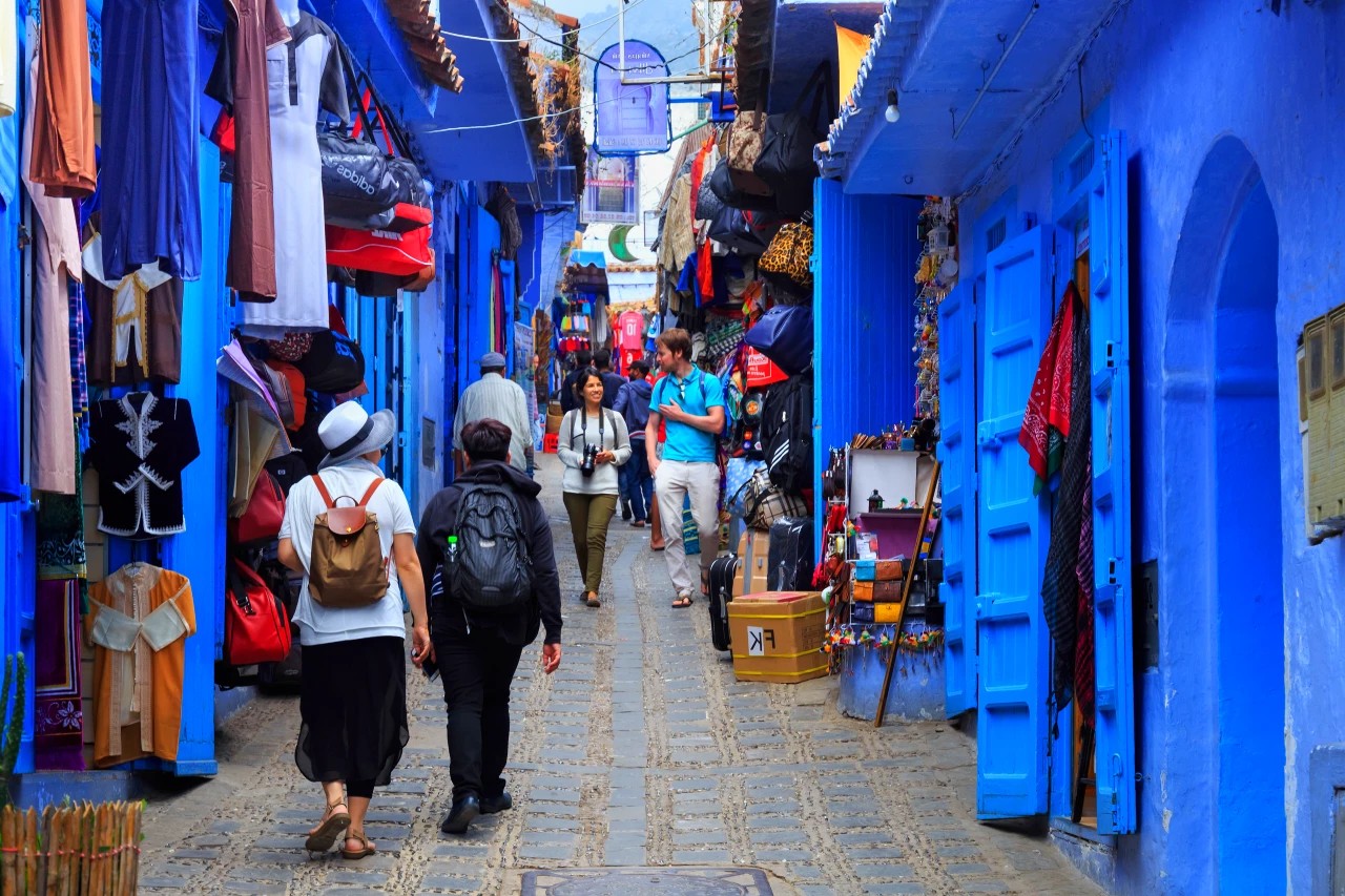 Tourists walking through the blue streets and market shops of Chefchaouen, Morocco