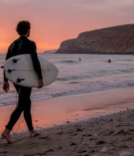 Surfer walking on Moroccan Atlantic coast beach