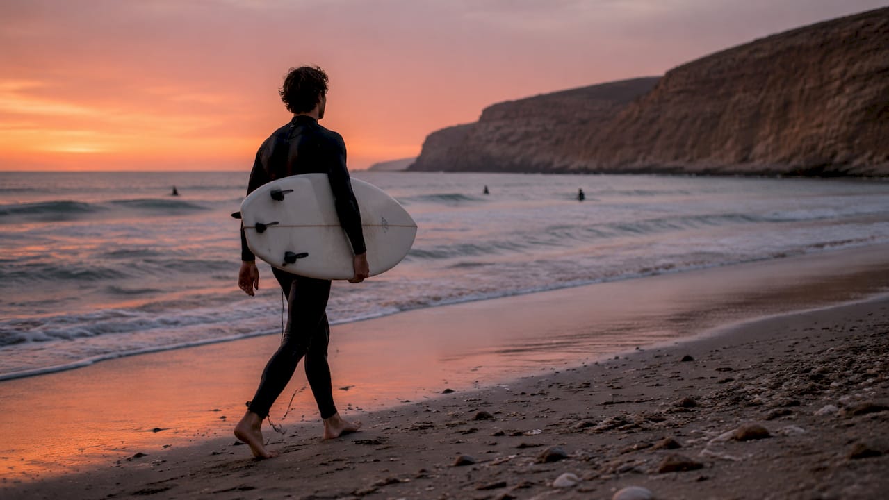 Surfer walking on Moroccan Atlantic coast beach