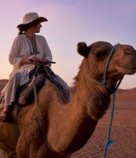 Traveler starting camel trek on Merzouga dunes